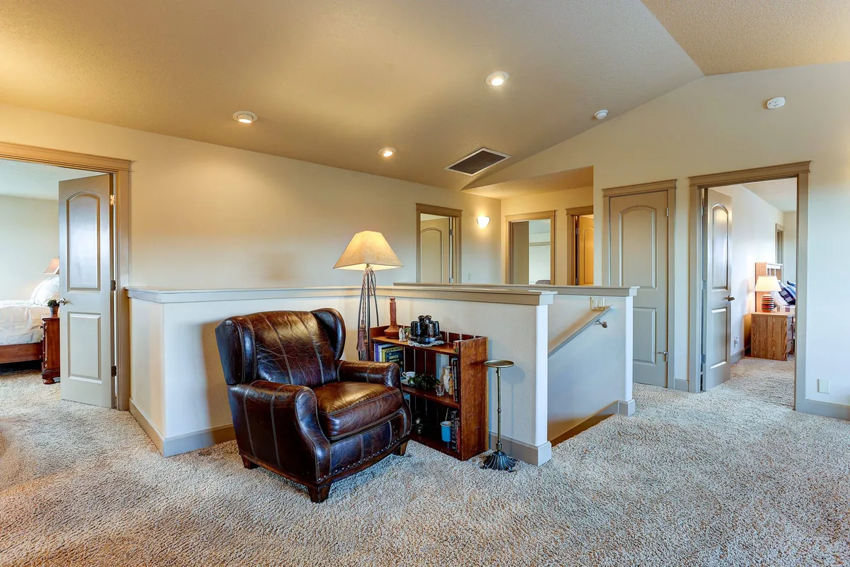 A cozy leather chair sits next to a lamp and a bookshelf stocked with books, creating a perfect nook for reading, working, or unwinding. The soft lighting and inviting atmosphere suggest a quiet, productive space ideal for focused work or creative brainstorming.