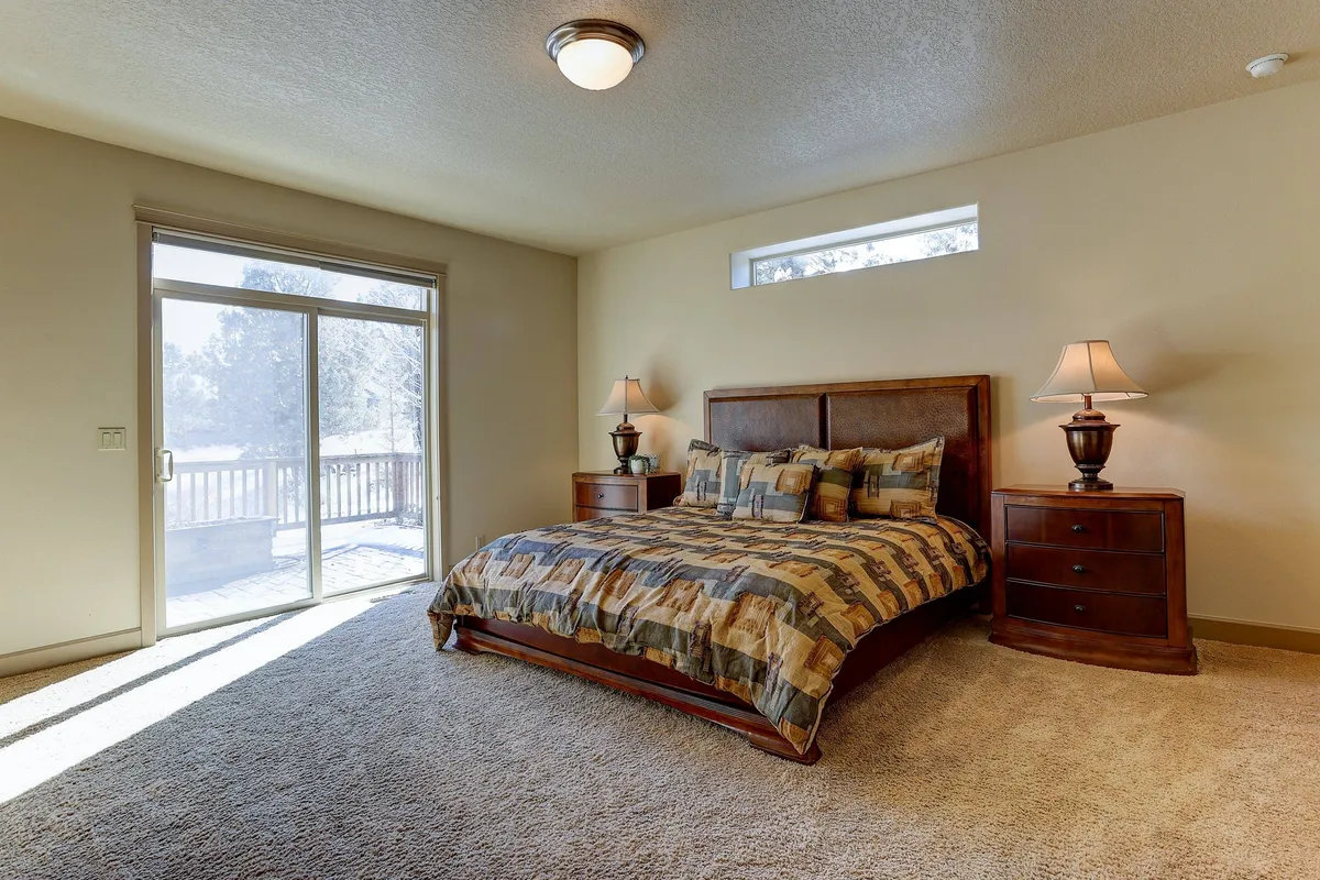 A bright, restful bedroom featuring a comfortable bed with a sliding glass door that allows in abundant natural light. The room is accented by nightstands and lamps, creating a serene and inviting ambiance ideal for relaxation or reading.