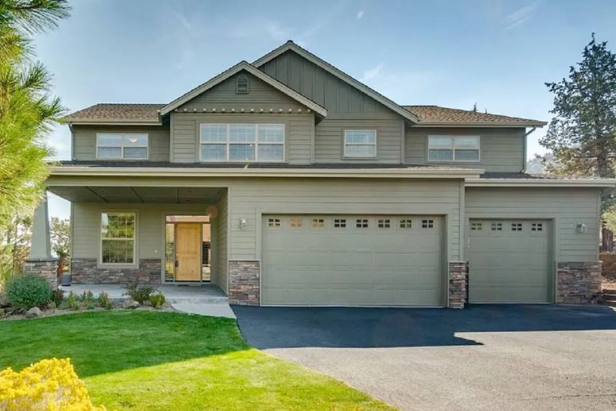 The image showcases the inviting front entrance of a spacious single-family home in Eagle Crest Resort, featuring a two-car garage, meticulously landscaped garden, and a welcoming porch—perfect for summer evenings and family gatherings. The overall mood is friendly and welcoming, with hints of outdoor fun and relaxation.
