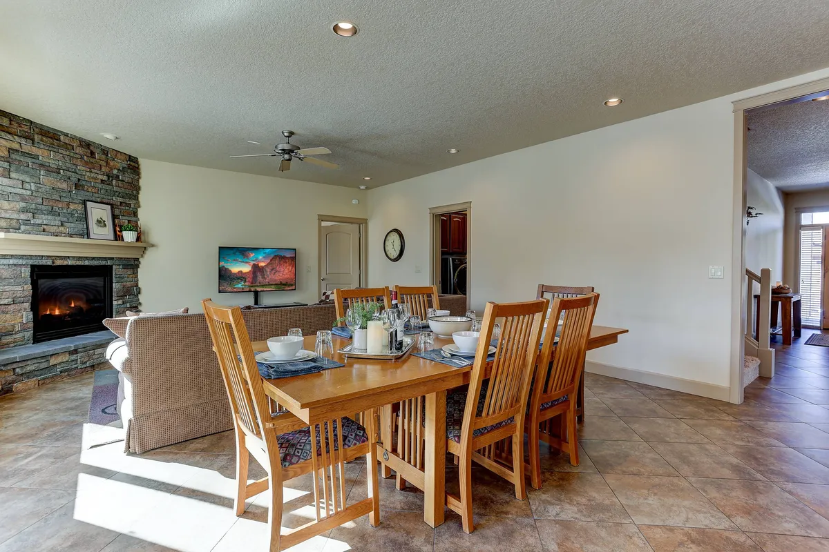 A warm, inviting living area centered around a dining table, with a cozy fireplace, television, and comfortable seating. The scene suggests a space ideal for group meals, socializing, and relaxed gatherings after a productive day.